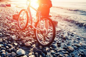 Cyclist on a pebble beach at sunrise