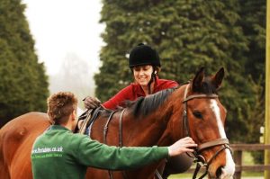 Horse rider and trainer getting on a horse