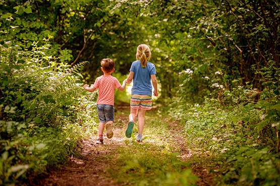 Two children running down a country path on summer holiday in West Sussex