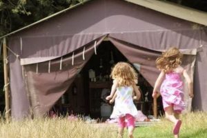 Two young girls running into yurt at Canfield Farm
