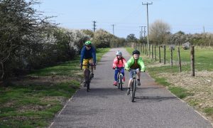 A family cycling on a path from Pagham to Medmerry