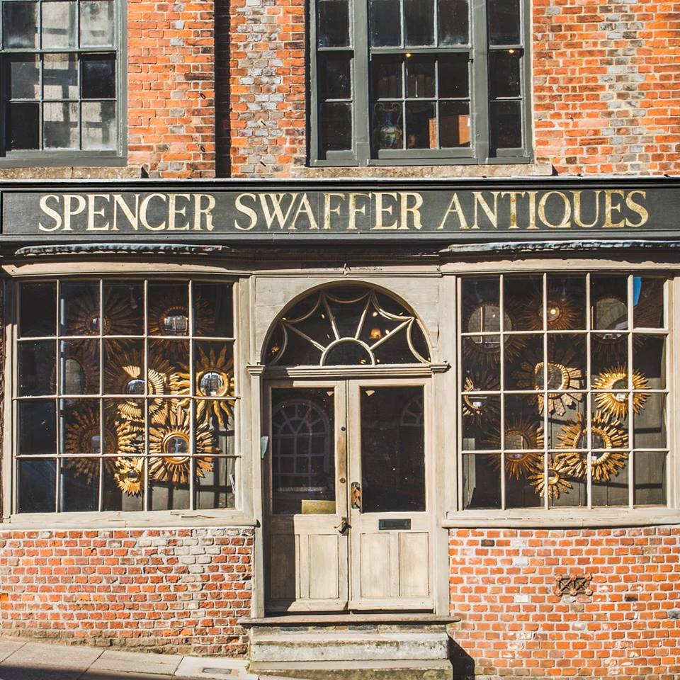 Historic red brick frontage of Spencer Swaffer Antisues shop with wooden double doors and mirrors in the window
