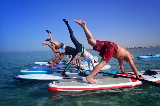Brighton Kitesurf SUP Academy teaching SUP yoga to a group on the water