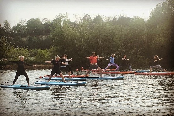A group of people trying out SUP yoga on a river in Sussex