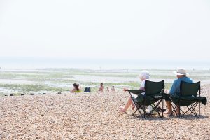 An older couple on camping chairs enjoying the beach scenery