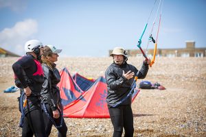 A couple learning to kitesurf with an instructor on Lancing beach