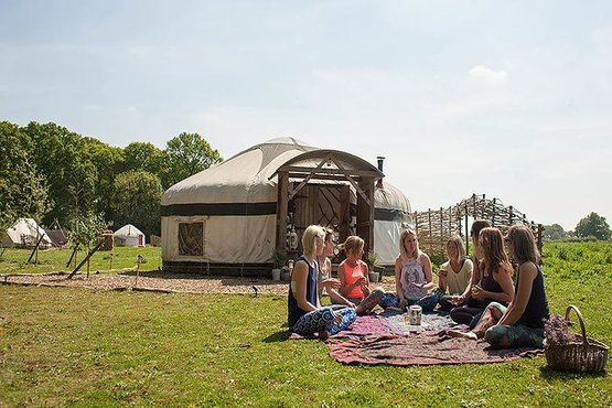 Group of women infront of glamping accommodation enjoying a picnic in the sunshine