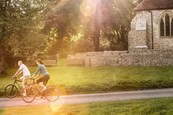 A couple cycling in the countryside infron of a church in Sussex
