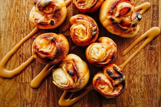 Pizza dough balls drizzled in sauce on a board