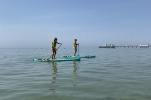 Two paddleboarders in the water by Worthing Pier
