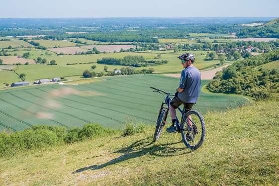 Male cyclist sitting back on bike overlooking the South Downs