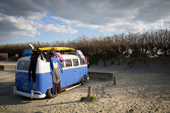 A classic campervan parked up at West Wittering Beach with surfboards atop