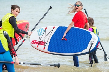 a family enjoying a watersports weekend with paddle boards in the sea in West Sussex