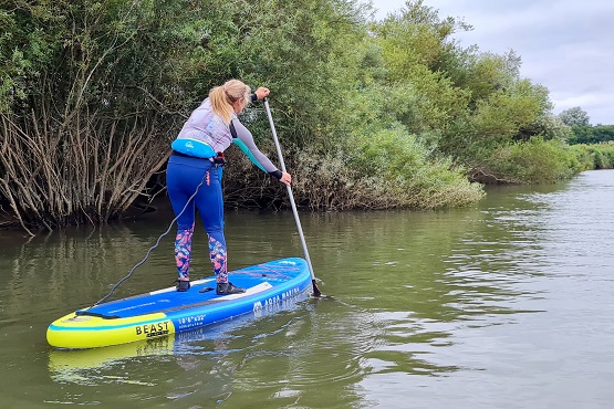 A woman paddle boarding on a river