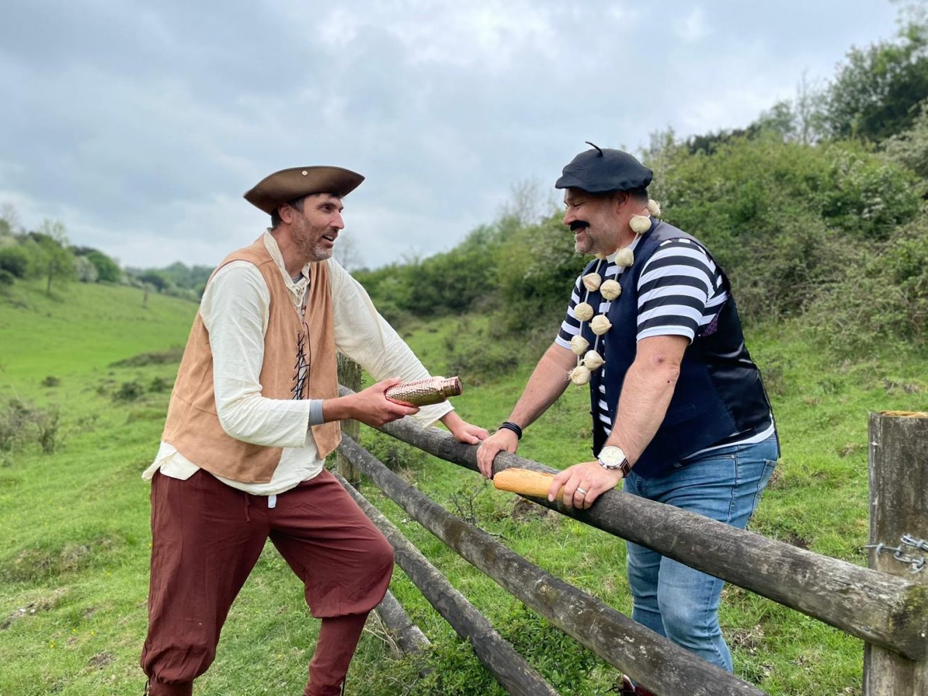 Two men chatting in a field over a fence