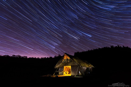 Shooting stars above a countryside cabin at night