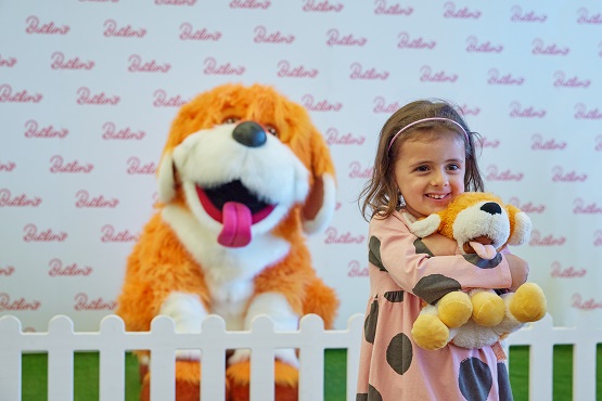 A girl cuddling a toy in front of a large dog